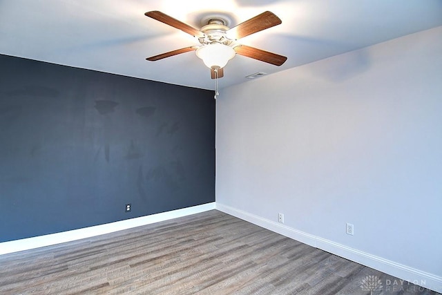 spare room featuring ceiling fan, wood finished floors, visible vents, and baseboards