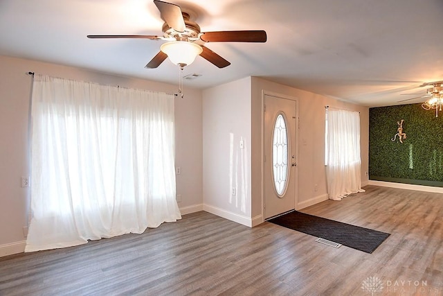 foyer featuring baseboards, visible vents, ceiling fan, and wood finished floors