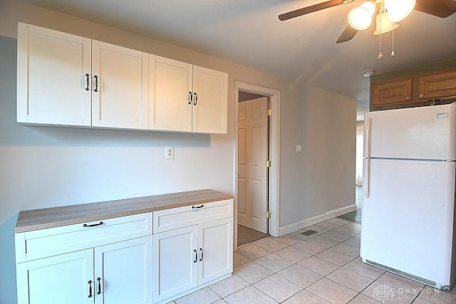 kitchen featuring light tile patterned floors, ceiling fan, white cabinets, and freestanding refrigerator