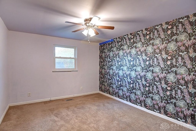 carpeted spare room with ceiling fan, visible vents, and baseboards