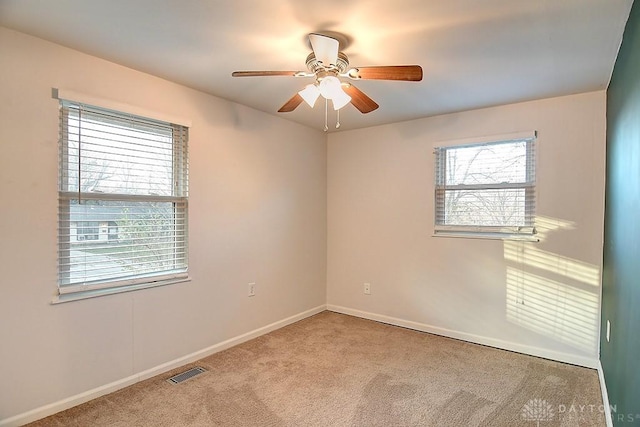 spare room featuring ceiling fan, carpet, visible vents, and baseboards