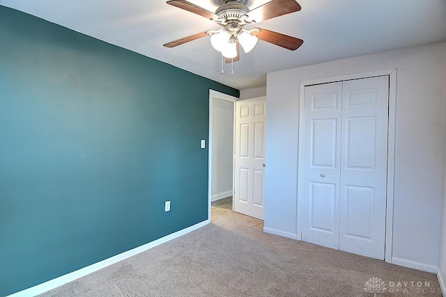 unfurnished bedroom with ceiling fan, a closet, baseboards, and carpet flooring