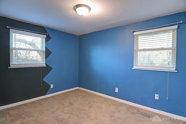 empty room with carpet floors, baseboards, and visible vents