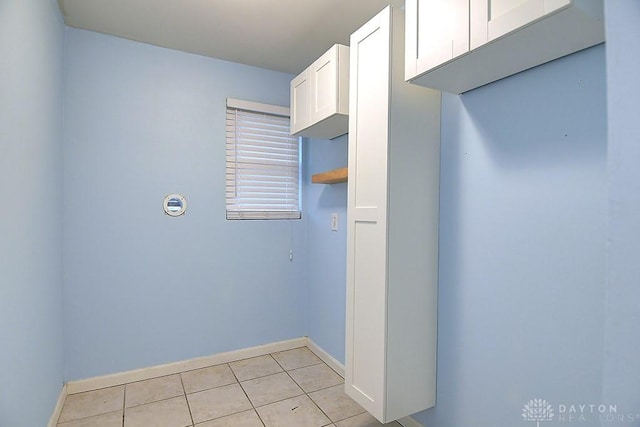 clothes washing area with baseboards and light tile patterned floors