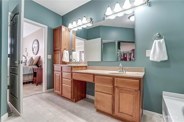 full bath featuring a sink, baseboards, a bath, double vanity, and ensuite bath