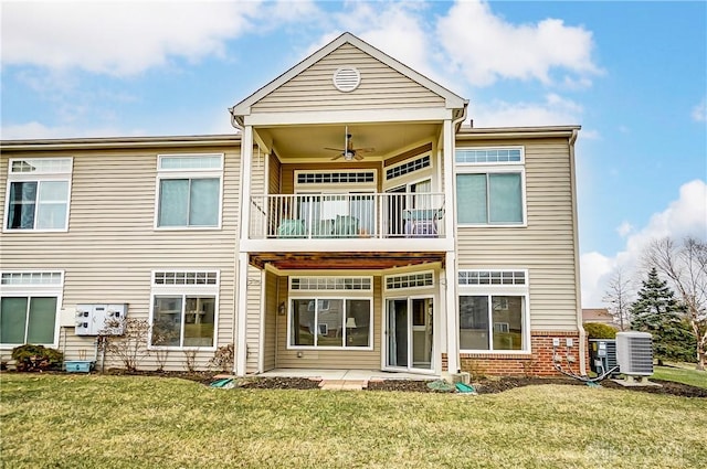 back of property featuring a ceiling fan, brick siding, a yard, and a balcony