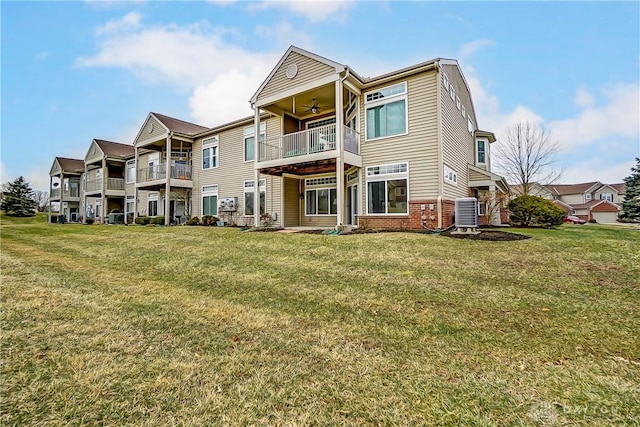 back of property featuring ceiling fan, a lawn, and brick siding