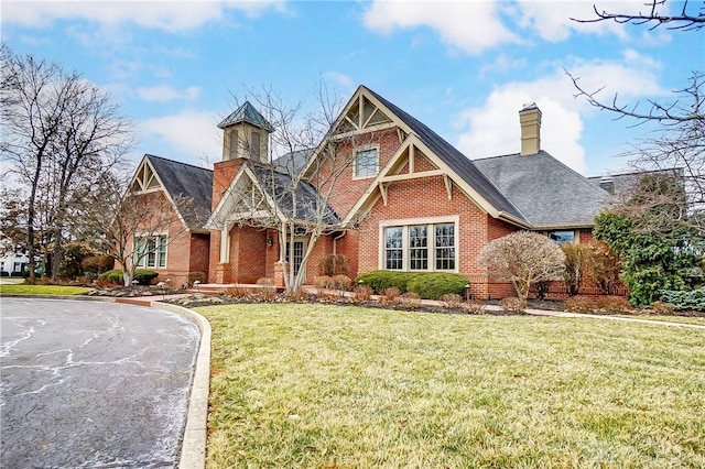 view of front of home featuring a chimney, a front lawn, and brick siding