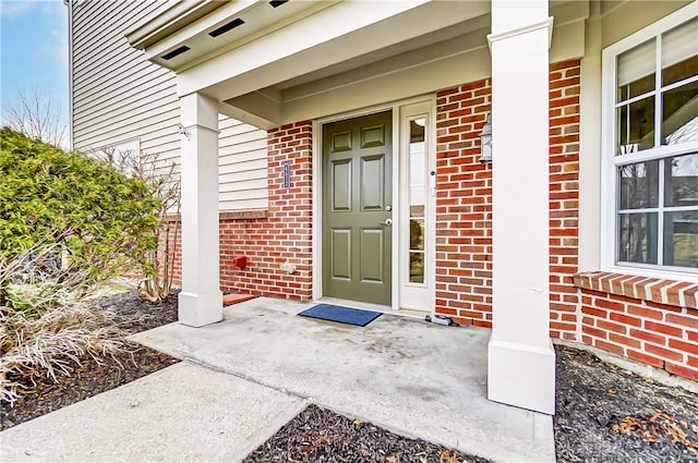 property entrance with covered porch and brick siding