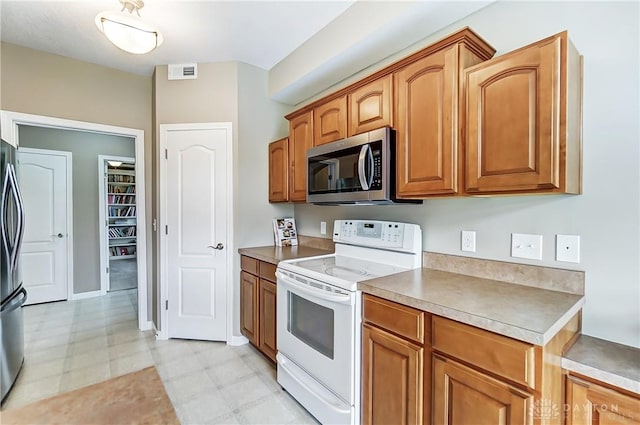 kitchen with brown cabinets, light floors, visible vents, and stainless steel appliances