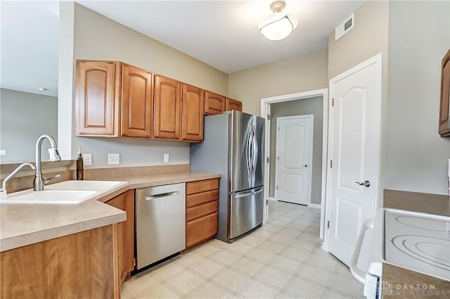 kitchen with visible vents, stainless steel appliances, light countertops, light floors, and a sink