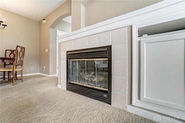 room details with a tiled fireplace, baseboards, arched walkways, and carpet flooring