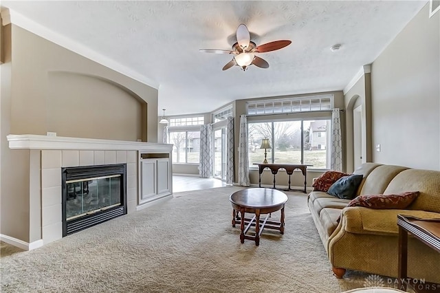 carpeted living room with baseboards, visible vents, a ceiling fan, and a tiled fireplace