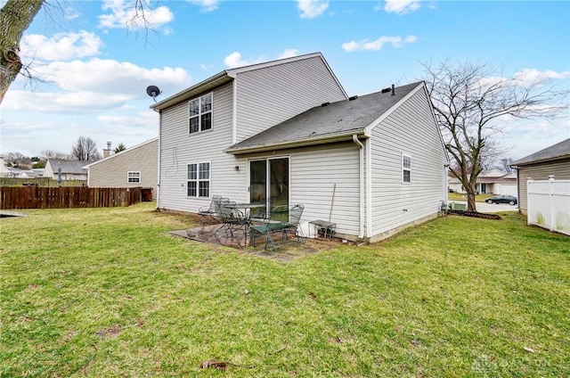 rear view of house with fence, a lawn, and a patio area