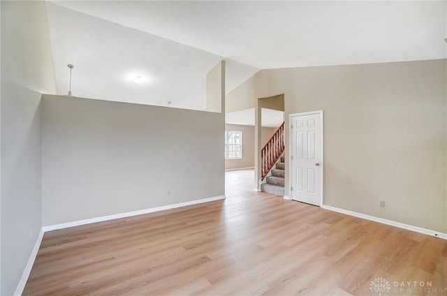 spare room with light wood-style flooring, stairs, and baseboards