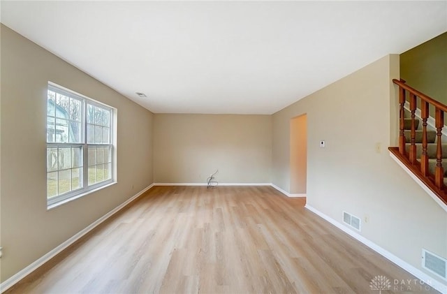 spare room with visible vents, baseboards, light wood-style flooring, and stairs