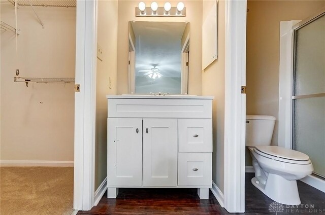 full bathroom with a shower with door, toilet, vanity, and baseboards