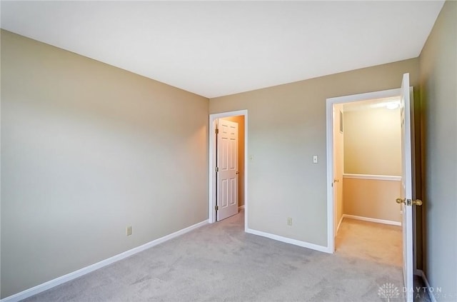 unfurnished bedroom with light colored carpet and baseboards