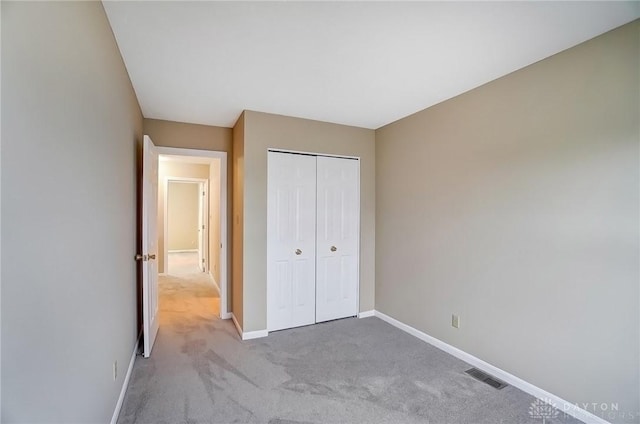 unfurnished bedroom with carpet, baseboards, visible vents, and a closet