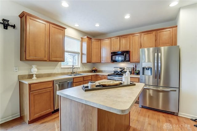 kitchen featuring stainless steel appliances, light wood-type flooring, a sink, and light countertops