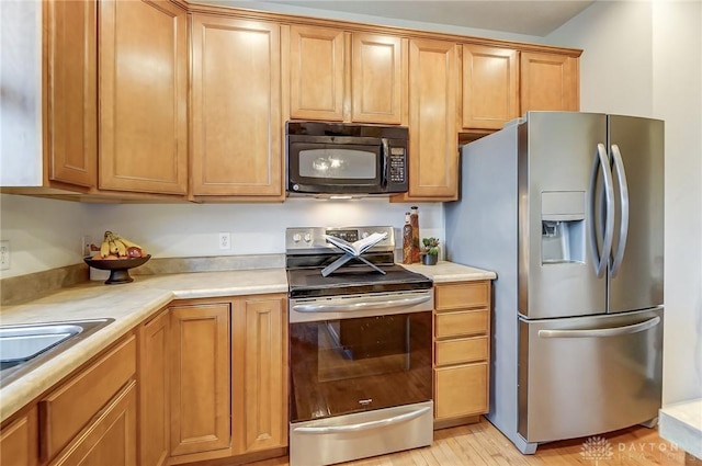 kitchen featuring appliances with stainless steel finishes, brown cabinetry, and light countertops