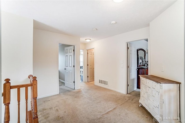 spare room featuring baseboards, visible vents, and light colored carpet