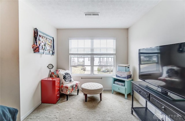 sitting room with a textured ceiling, carpet flooring, visible vents, and baseboards