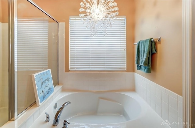 bathroom featuring a garden tub and an inviting chandelier