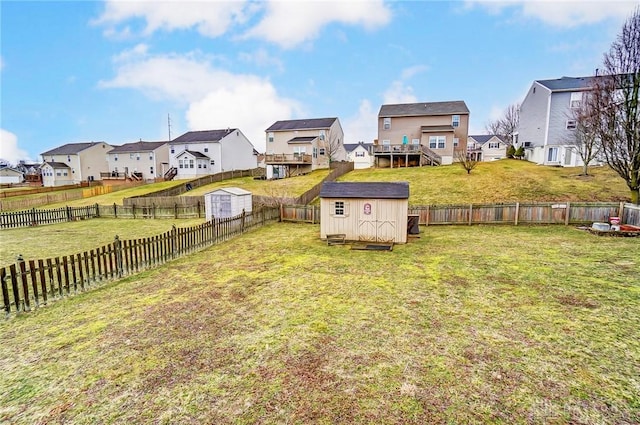 view of yard with a residential view, a fenced backyard, an outdoor structure, and a storage shed