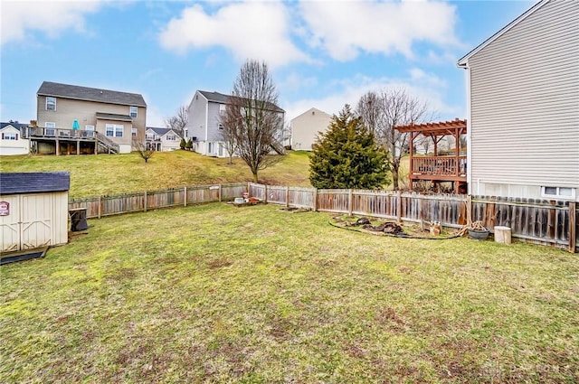 view of yard with an outbuilding, a fenced backyard, a shed, and a pergola