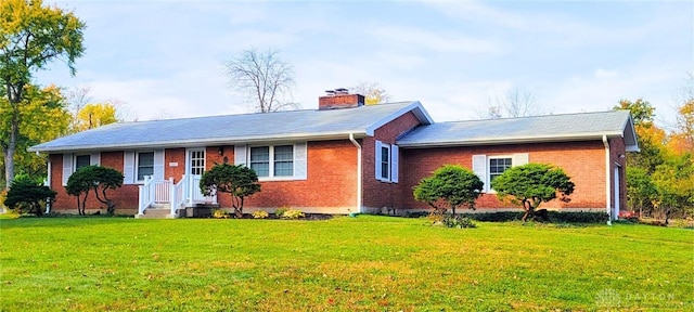 ranch-style home with a chimney, a front lawn, and brick siding