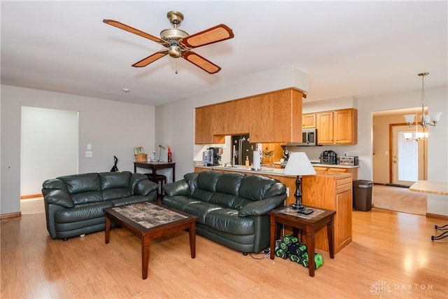 living room featuring light wood finished floors and ceiling fan with notable chandelier