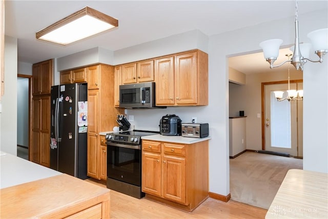 kitchen featuring light countertops, an inviting chandelier, appliances with stainless steel finishes, light wood-style floors, and baseboards