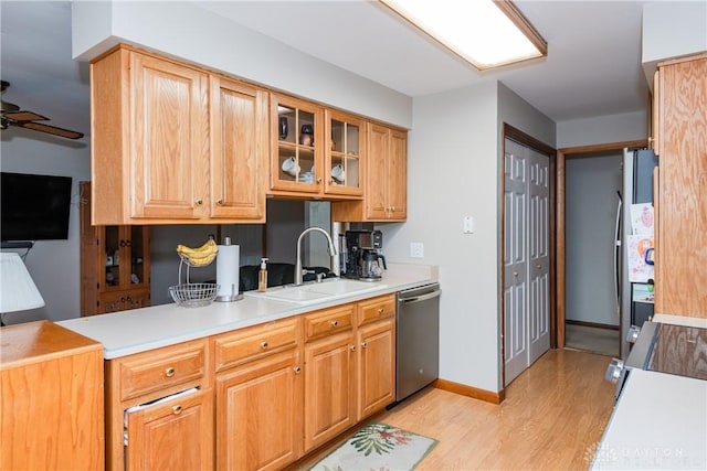 kitchen featuring stainless steel appliances, light countertops, light wood-style flooring, a ceiling fan, and a sink