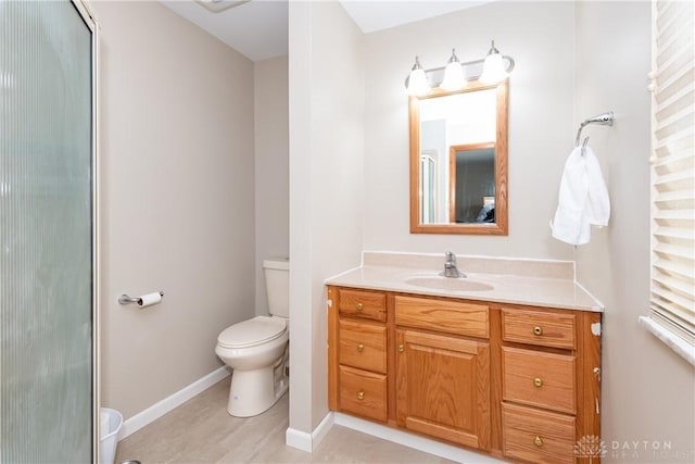 bathroom featuring toilet, baseboards, and vanity