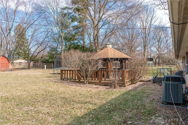 view of yard with a trampoline, fence, a gazebo, and central air condition unit