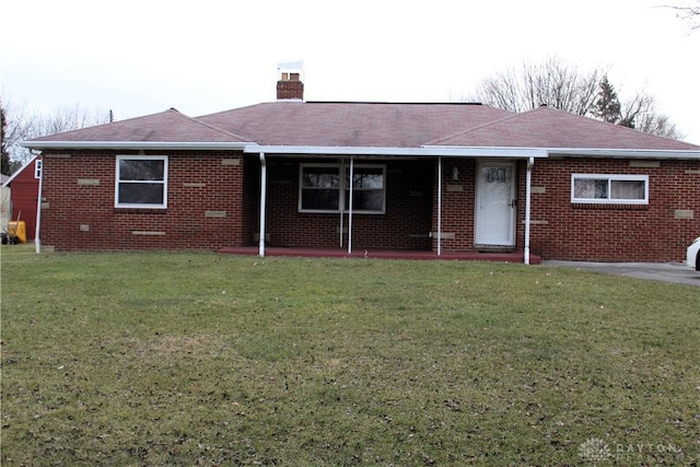 view of front of property with a front yard, brick siding, and a chimney