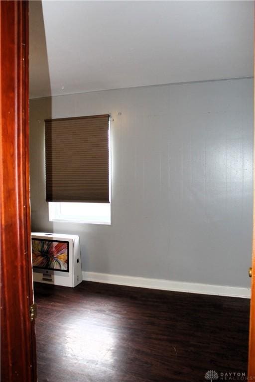 empty room with heating unit, baseboards, and wood finished floors