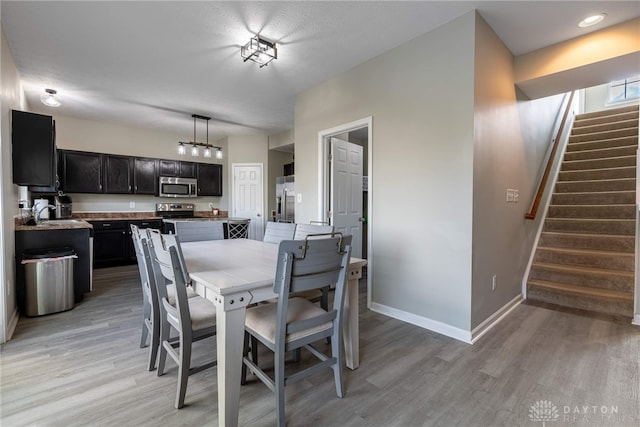 dining space with stairway, light wood-style flooring, and baseboards