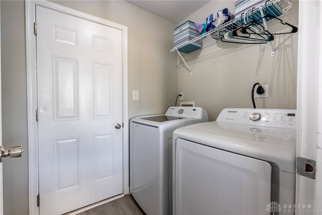 clothes washing area with a textured ceiling, laundry area, wood finished floors, and washer and dryer