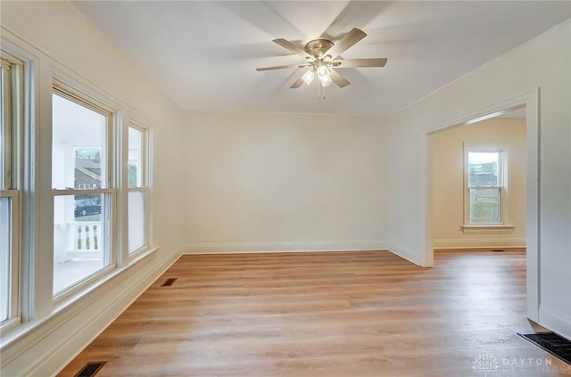 empty room with light wood-style floors, baseboards, visible vents, and a ceiling fan