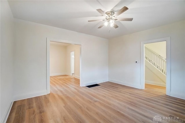 spare room with light wood-type flooring, baseboards, visible vents, and ceiling fan