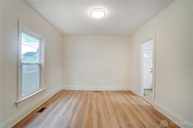 unfurnished room with visible vents, light wood-style flooring, and baseboards