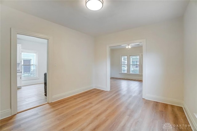 unfurnished room with a healthy amount of sunlight, light wood finished floors, and baseboards