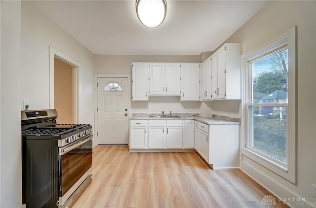 kitchen with gas stove, light countertops, a sink, and light wood finished floors