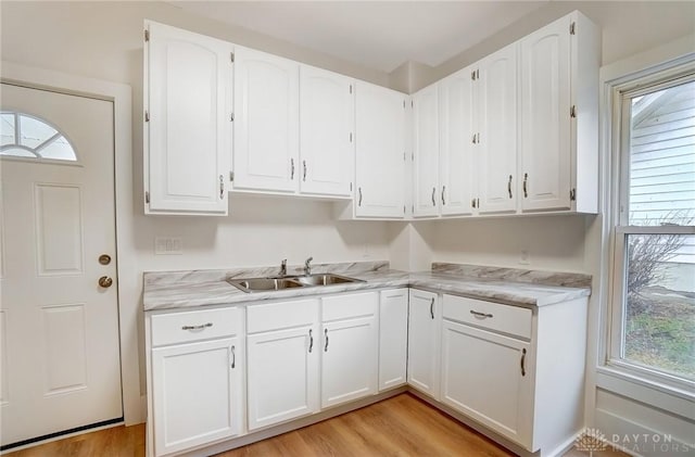 kitchen with light countertops, white cabinetry, and a sink