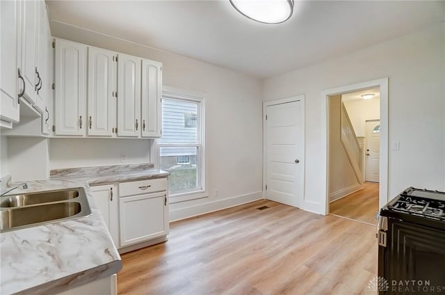 kitchen featuring light wood-type flooring, white cabinetry, and black range with gas stovetop