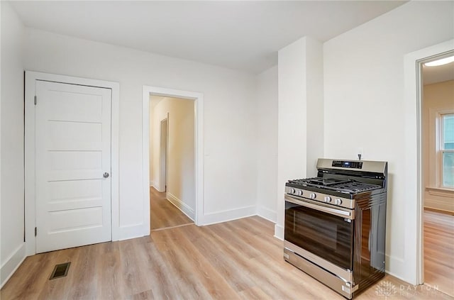 kitchen with light wood-style flooring, visible vents, baseboards, and gas stove