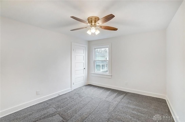 spare room with dark colored carpet, ceiling fan, and baseboards