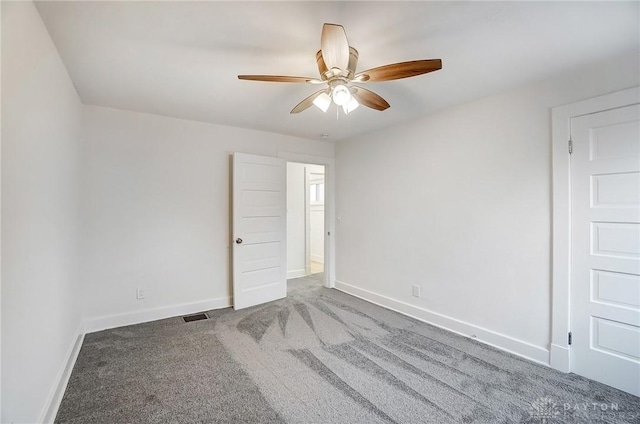 carpeted spare room featuring visible vents, baseboards, and ceiling fan